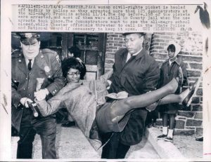 African American woman being carried away by police.