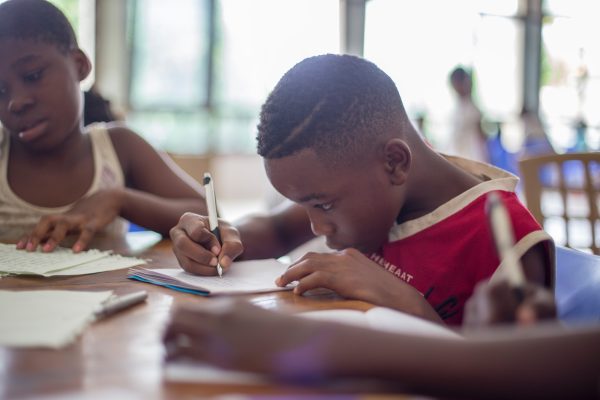 boy writing on printer paper near girl