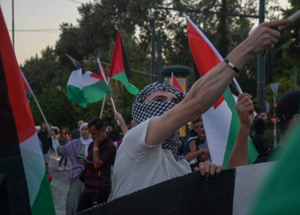 a group of palestinian protesters holding flags and wearing masks