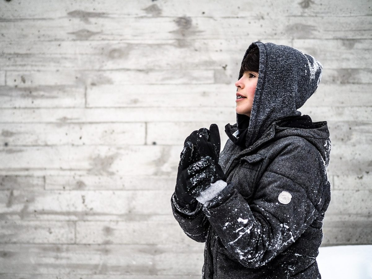 person+wearing+black+hooded+jacket+standing+beside+grey+wall