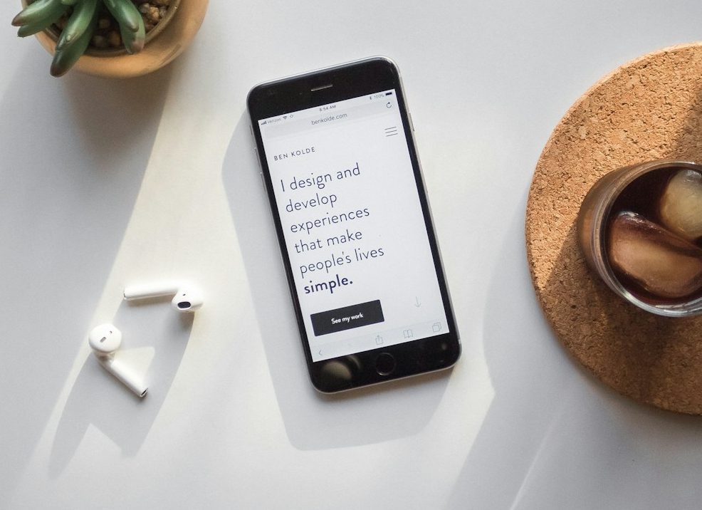 post-2014 iPhone beside Apple AirPods and succulent plant on white surface