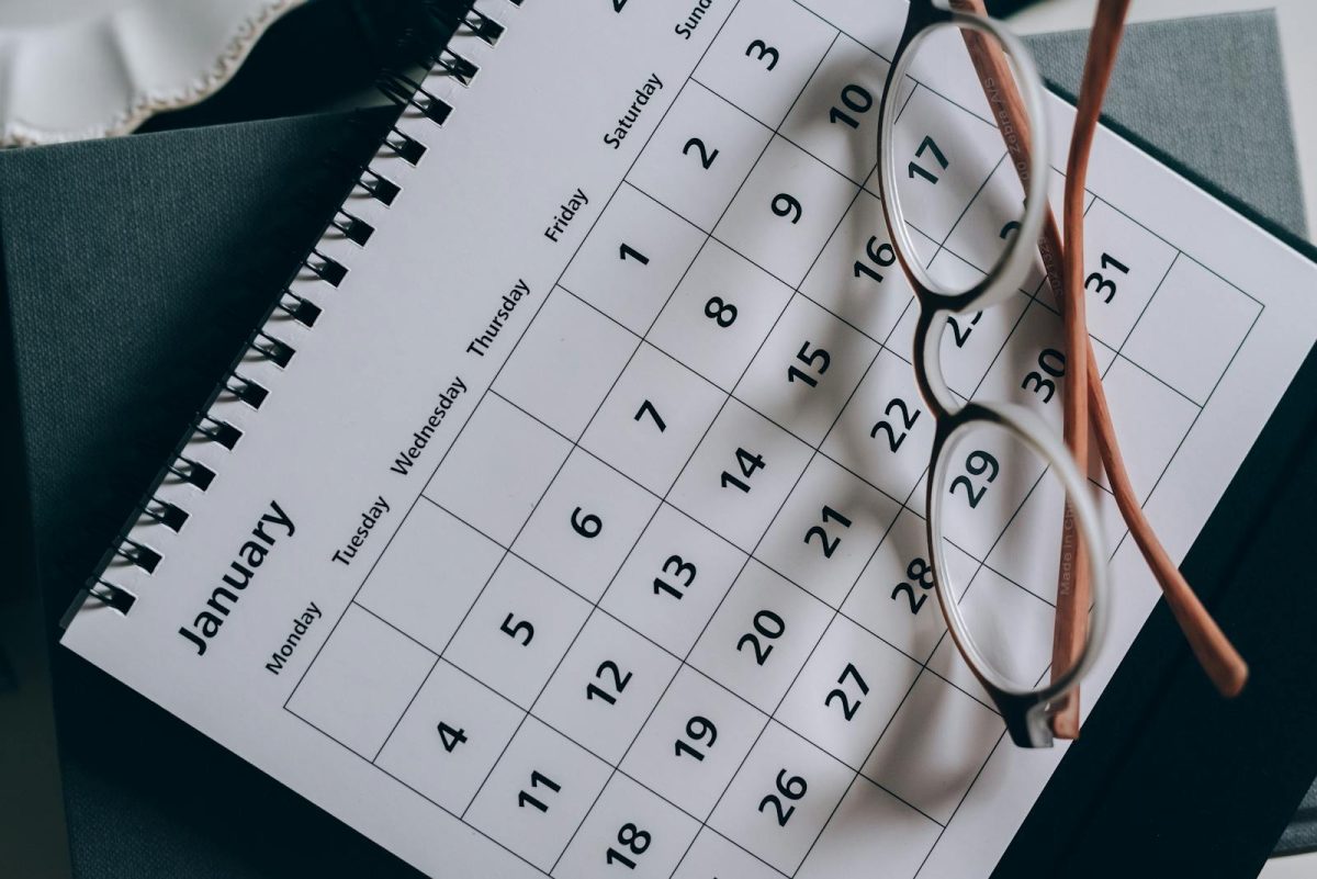 A close-up of a January calendar with eyeglasses on a table, emphasizing planning and organization.